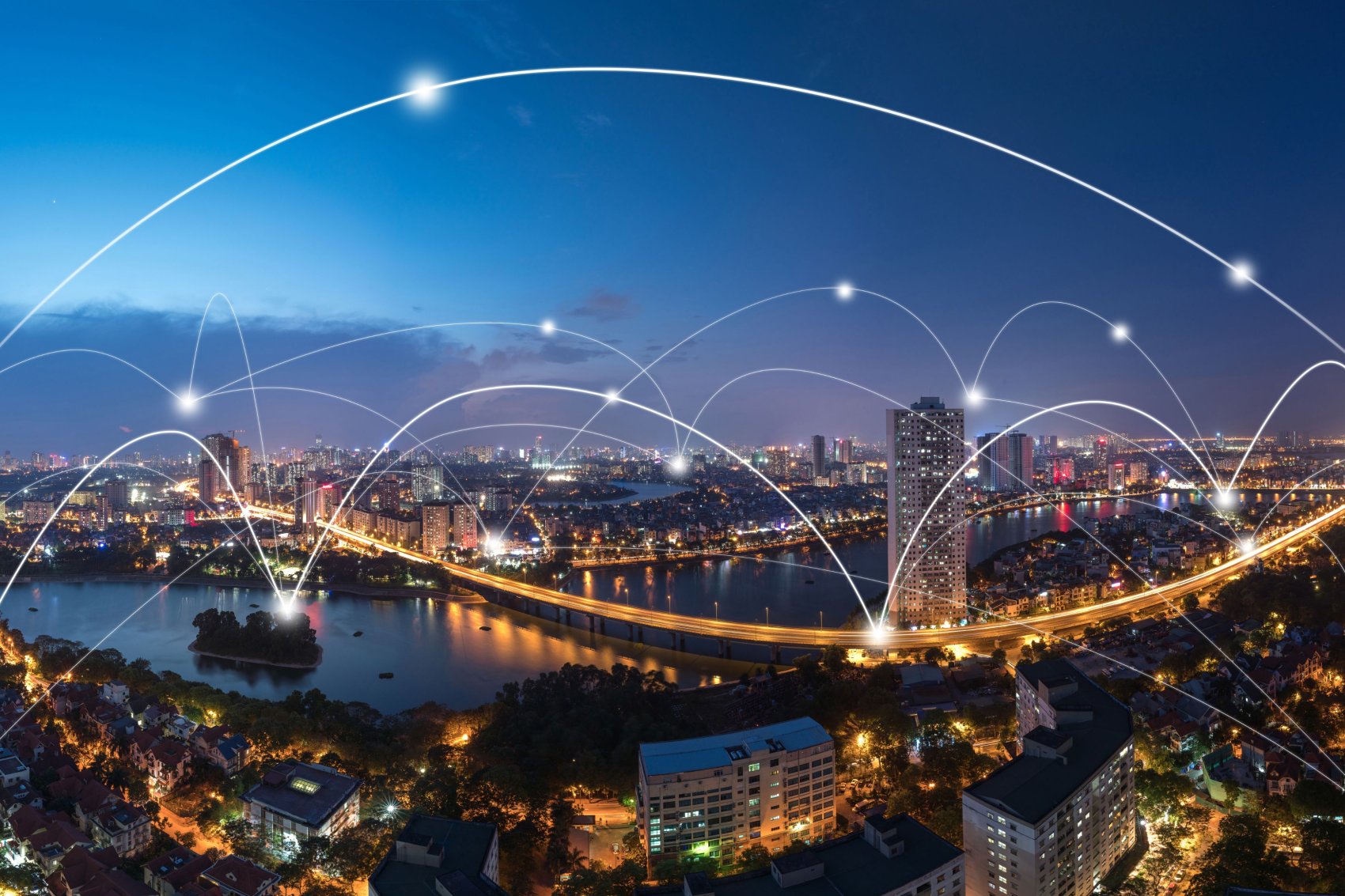 Nighttime cityscape with illuminated buildings and bridges, overlaid with white lines and dots symbolising digital connectivity and network infrastructure.