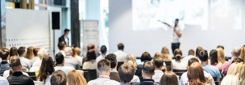 Engaged audience at a cyber security seminar, with a presenter at the front of the room.
