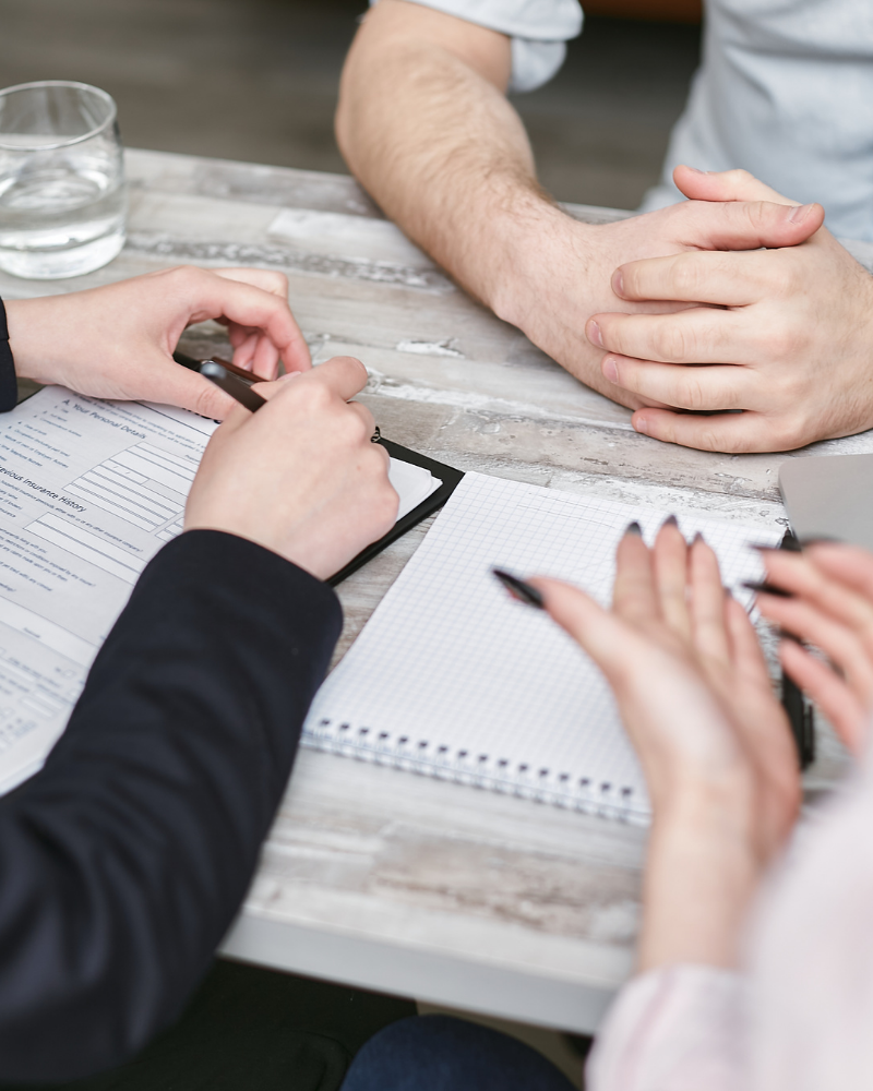 People collaborating around a table during a business consultation, reviewing documents and taking notes during a planning meeting.