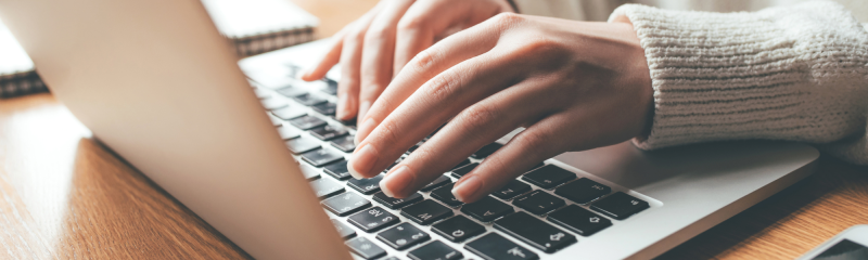 Close-up of hands typing on a MacBook keyboard, highlighting online communication concept