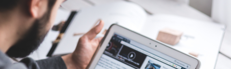 Blurred image of an individual reading a news article on a tablet device.
