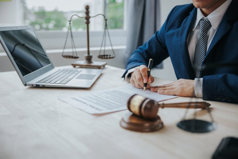 Lawyer writing contract next to PC