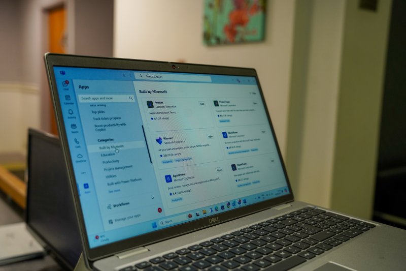 Dell laptop on a desk displaying Microsoft Office apps.